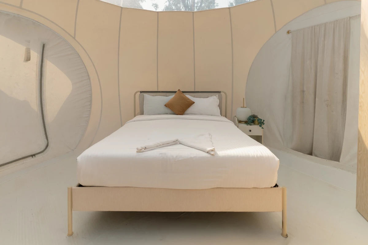 Cozy premium bed setup inside a scenic glamping bubble dome at boCHE 1000 Acre resort in Wayanad.