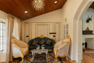 Elegant living space with royal gold-trimmed sofas and a spiky chandelier at boCHE 1000 Acre, one of the best resorts in Wayanad.